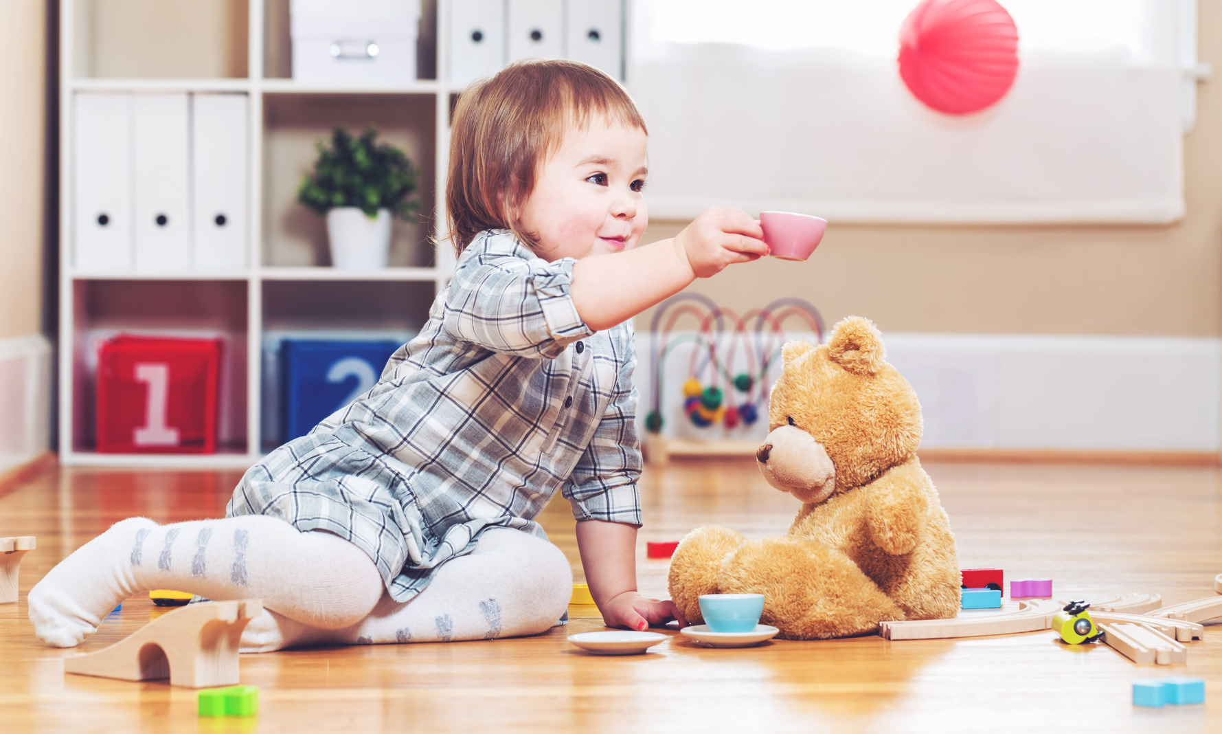 Happy toddler girl playing with her teddy bear